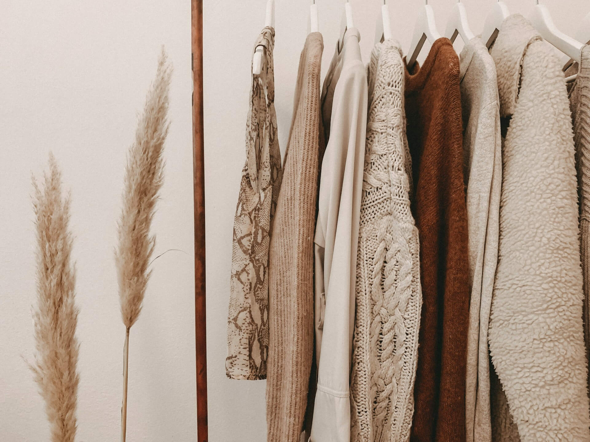 Neutral-toned sweaters hanging on a rack